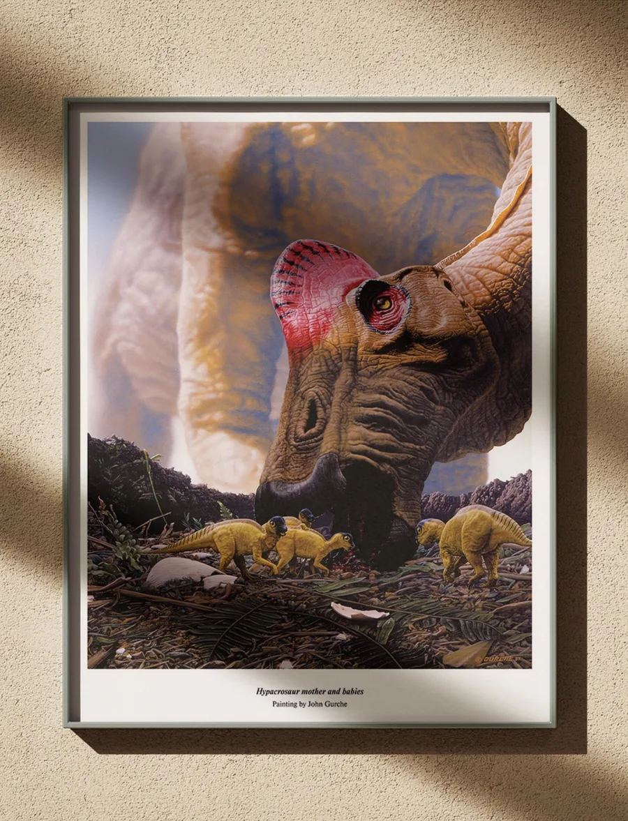 The Hypacrosaur mother and babies painting, framed in black on a warm plaster wall in low sun.